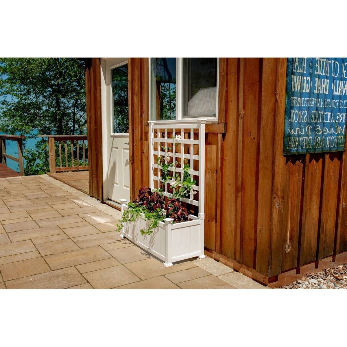 Outdoor White Vinyl Garden Planter Box with Trellis next to a wooden house, showcasing plants climbing the lattice.