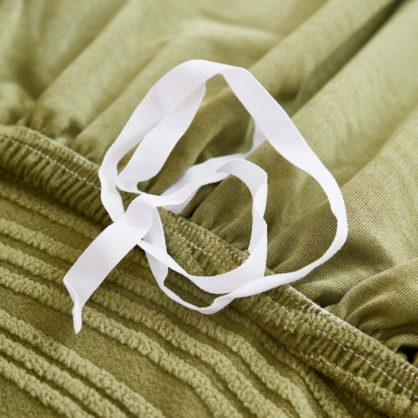 Close-up of green Textured Wave Stretch Sofa Couch Cover with white straps, Soft Washable Spandex Furniture Slipcovers detail.