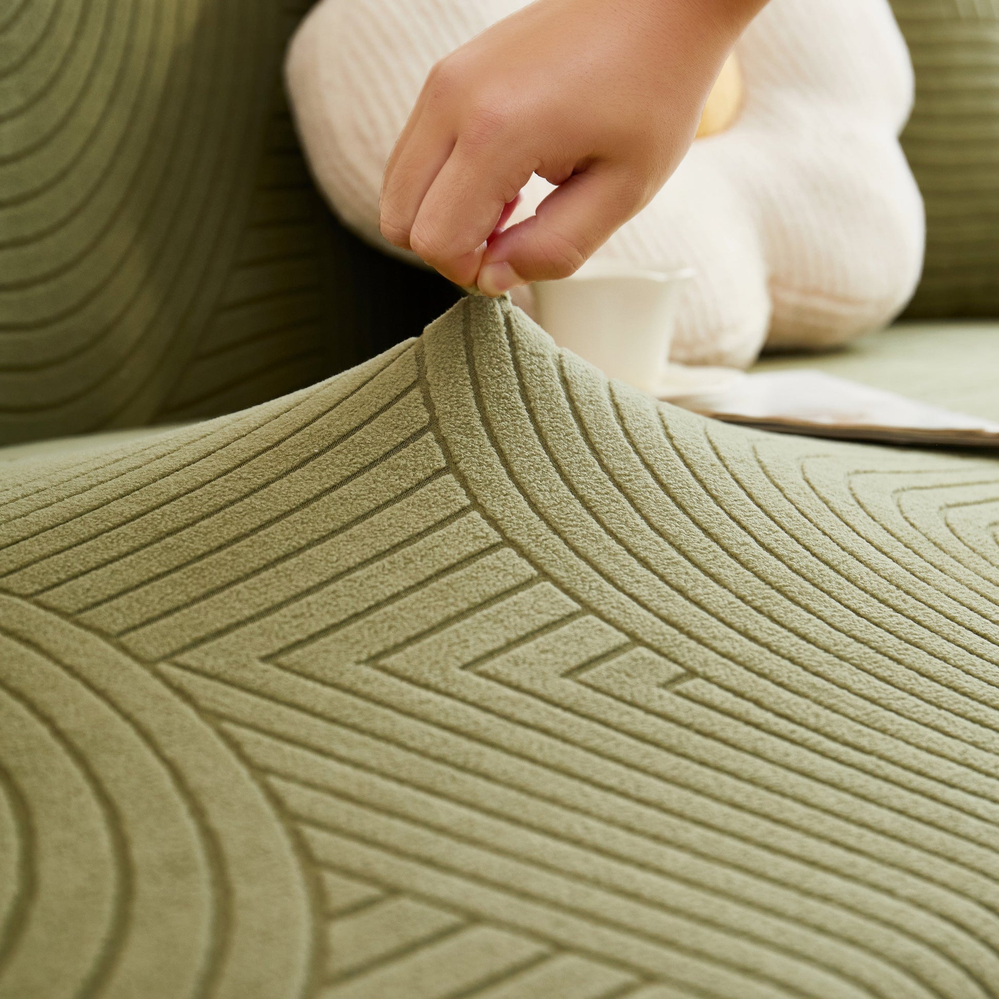 Hand adjusting a Fleece Stretch Sofa Slipcover Washable Soft Spandex Couch Cover Furniture Protector with geometric wave pattern.