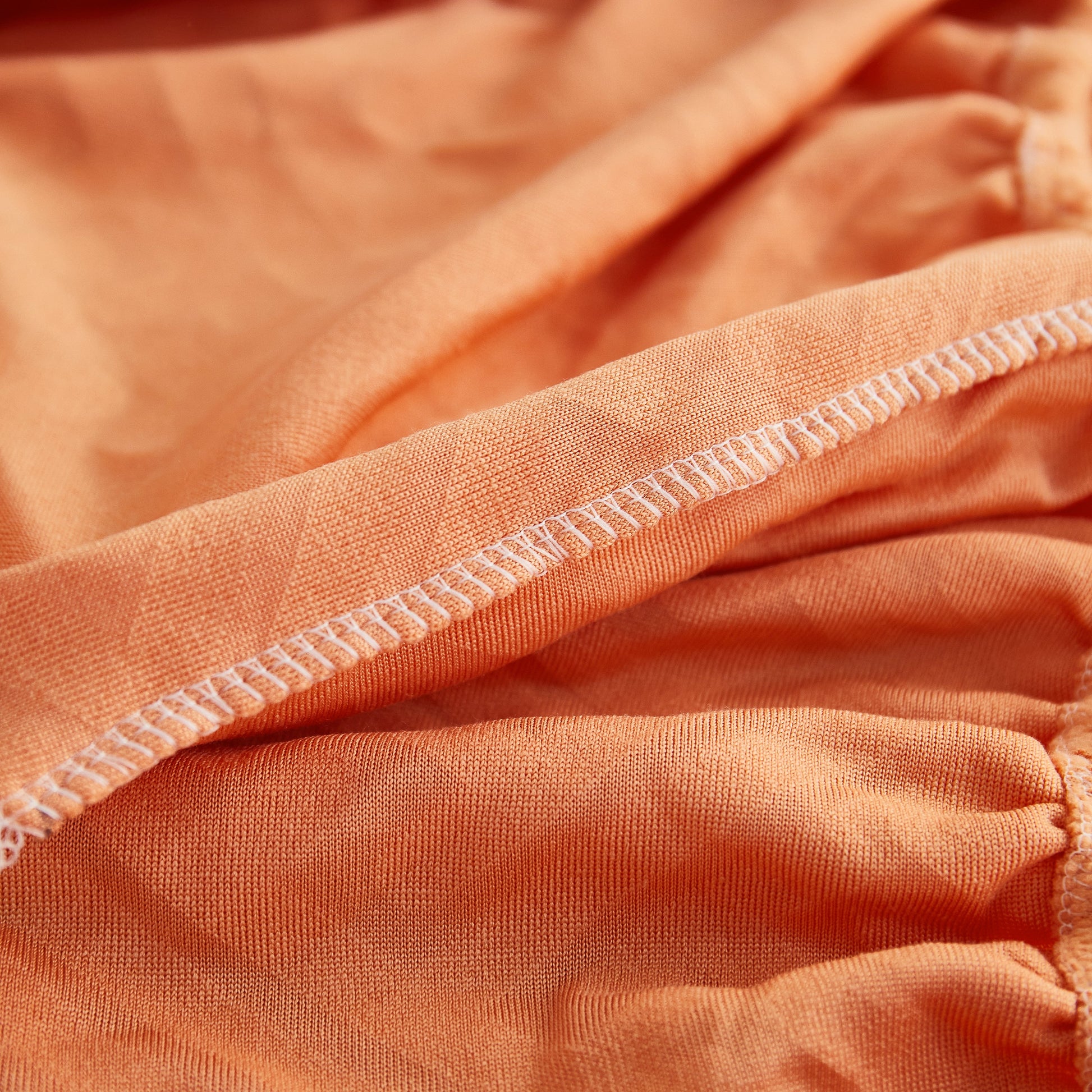 Close-up of orange Polar Fleece Couch Cushion Covers, Stretch Sofa Seat Cushion Covers showing elastic fabric details
