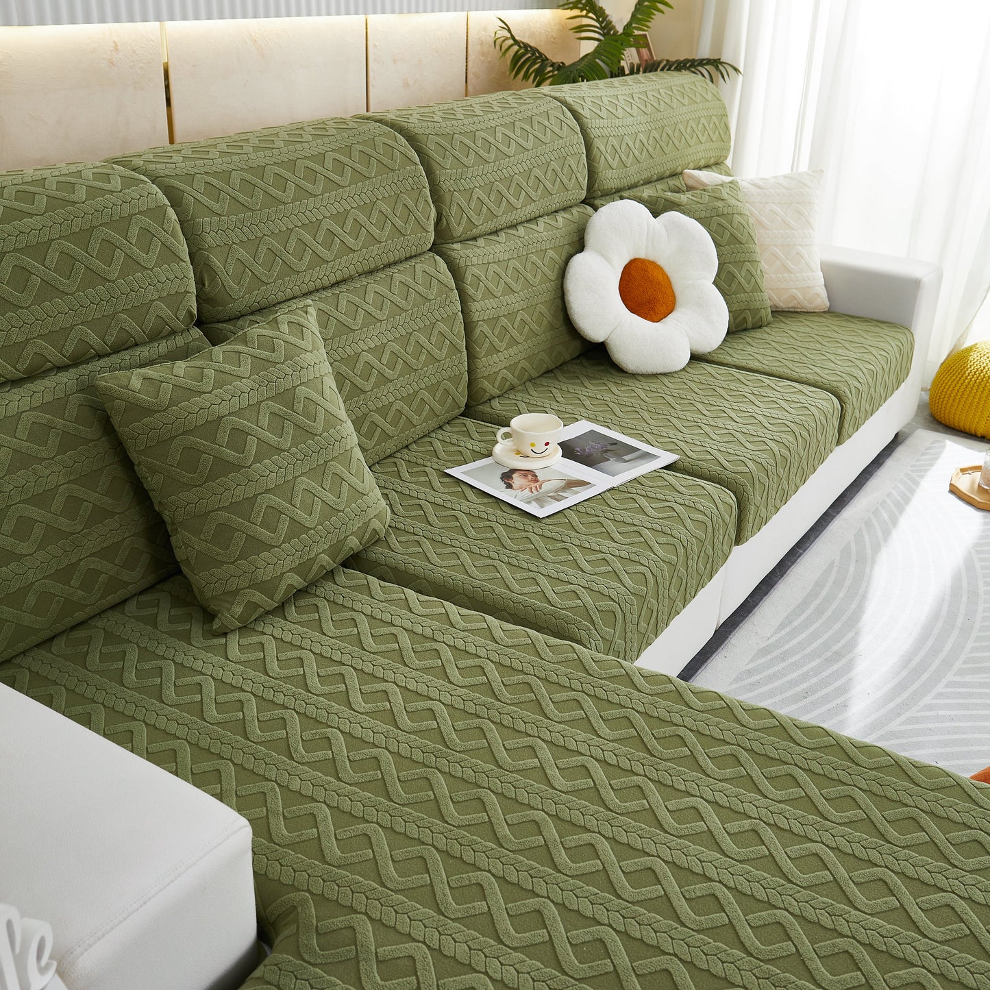 Green stretch couch seat cushion covers on a sofa with decorative throw pillows, showcasing soft flexibility and elastic bottom.