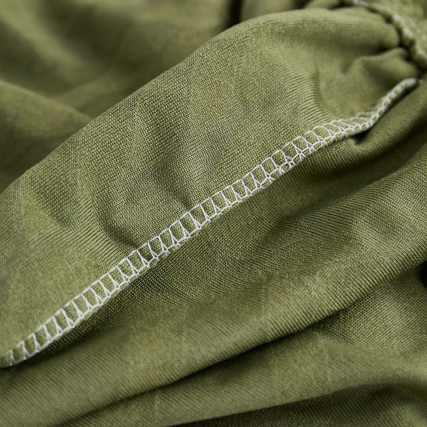 Close-up of green Stretch Couch Seat Cushion Covers, Sofa Slipcover Sofa Cover Soft Flexibility with Elastic Bottom stitching.