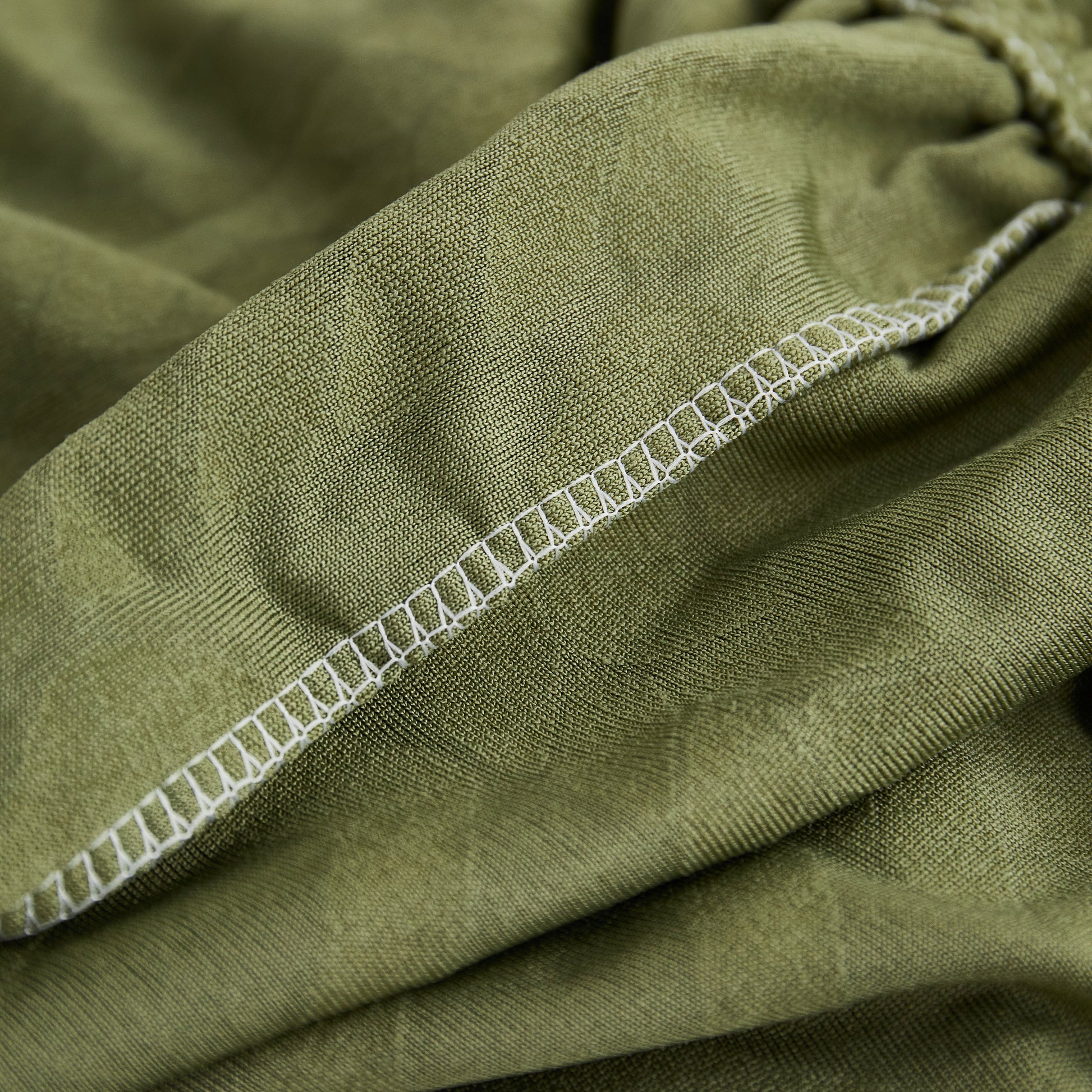 Close-up of green Stretch Couch Seat Cushion Covers, Sofa Slipcover Sofa Cover Soft Flexibility with Elastic Bottom stitching.