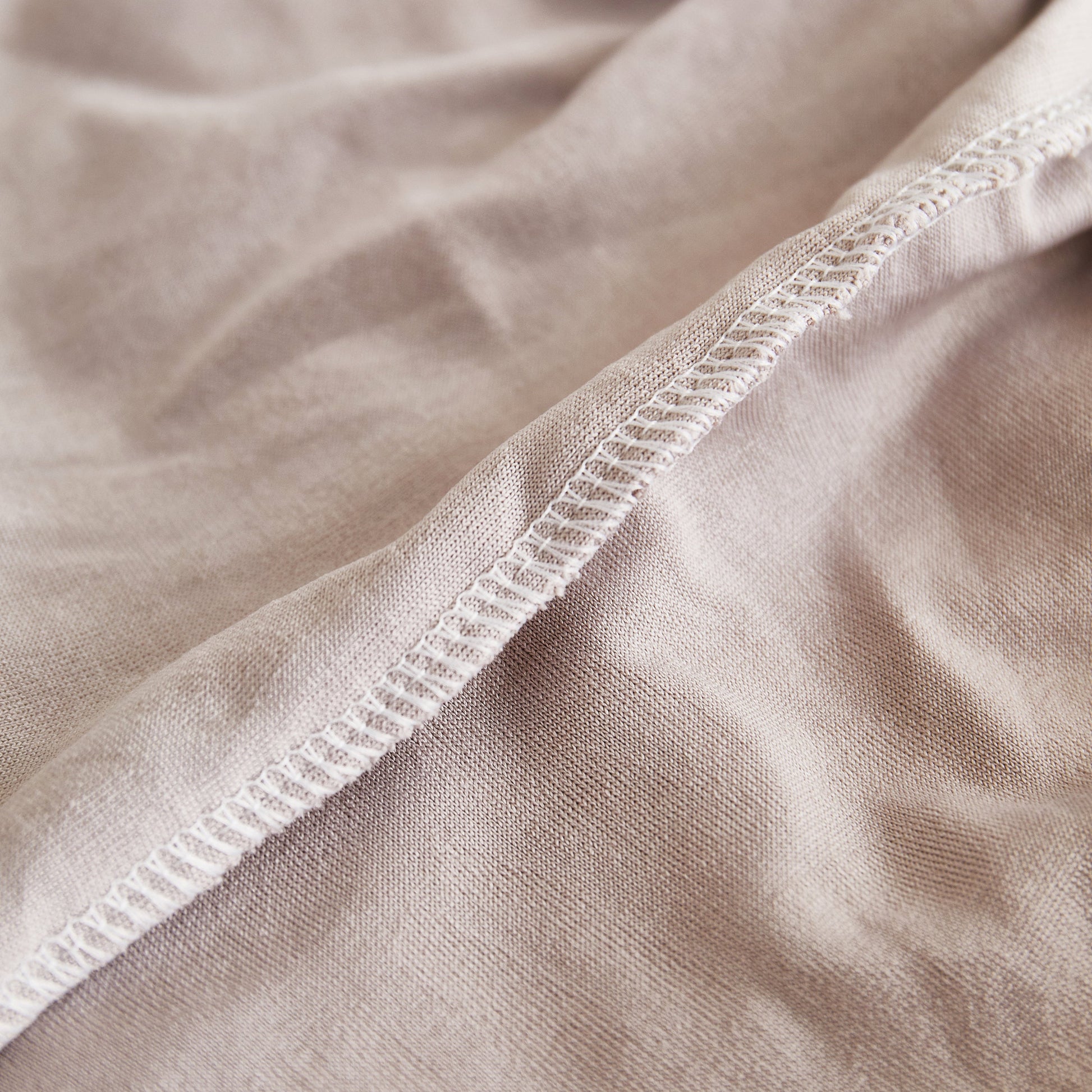 Close-up of a beige fabric showing seam and texture, ideal for concepts related to textiles and material quality.