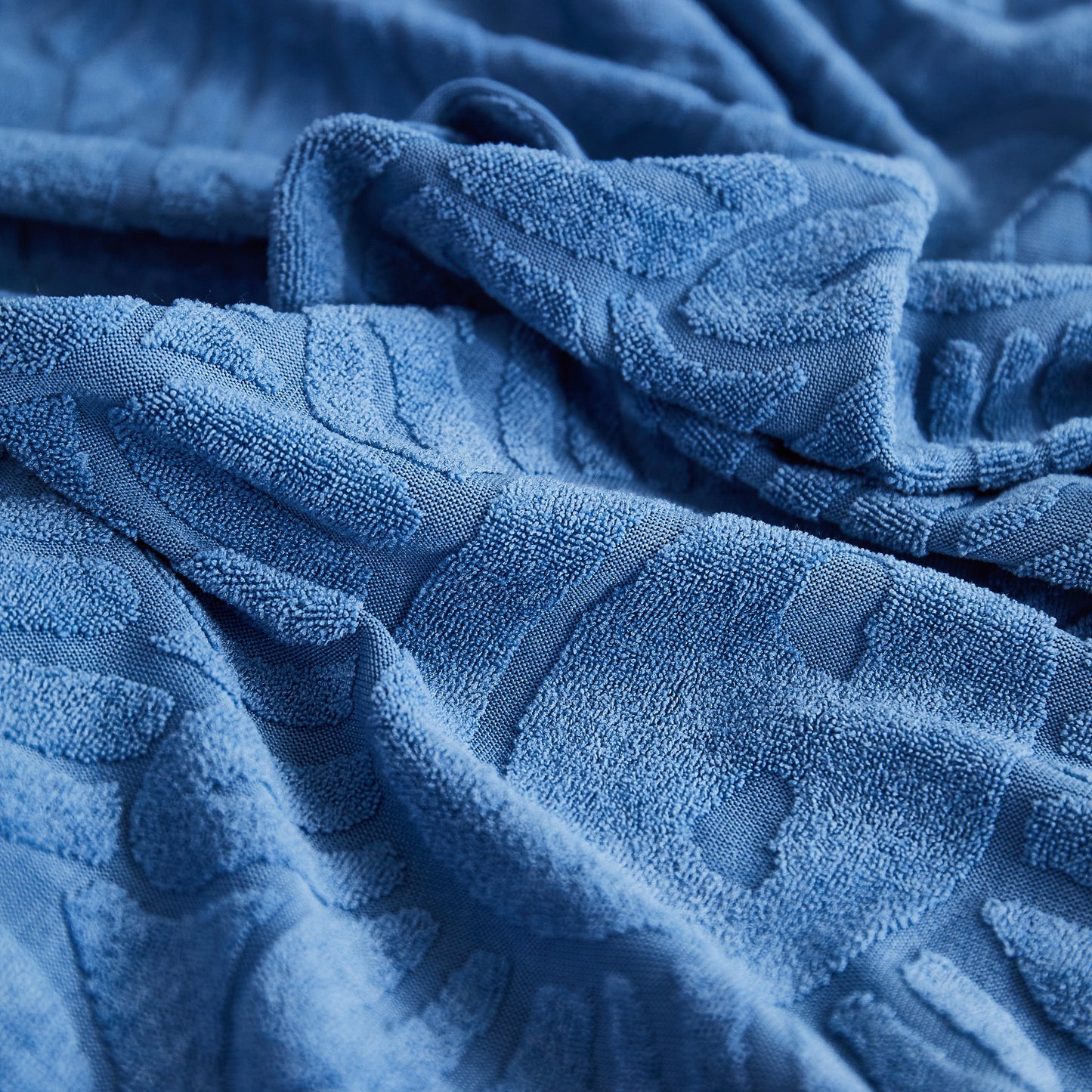 Textured blue fabric with a soft, detailed jacquard pattern.