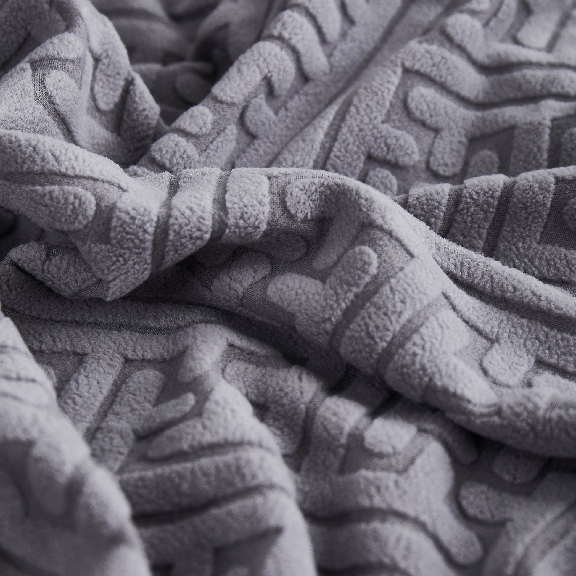 Close-up of gray textured fabric used in stretch sofa covers with skirt for couch seat and cushion, chaise, sectional, 1/2/3/4 seater sofas.