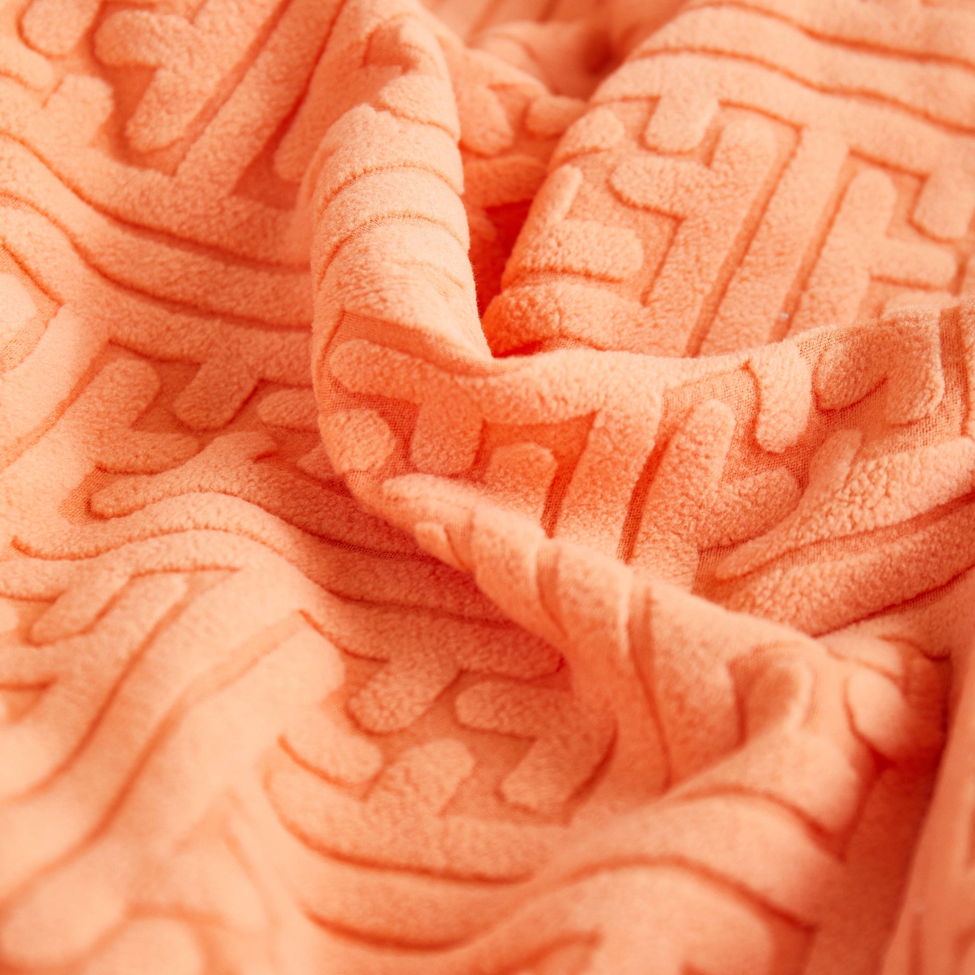 Close-up of orange textured fabric with embossed patterns for decorative upholstery.