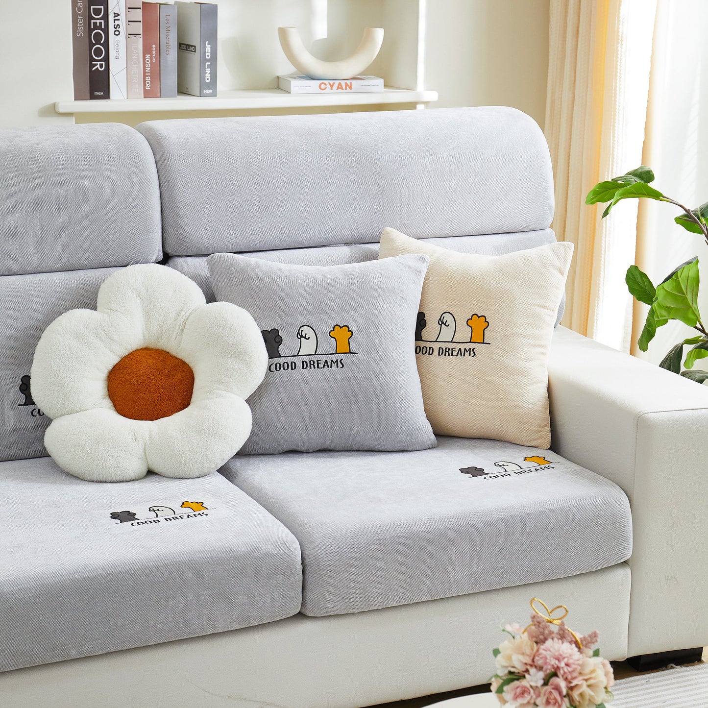 Cozy living room setup with grey and beige couches featuring decorative cushions and a fun flower pillow, enhancing relaxation and style.