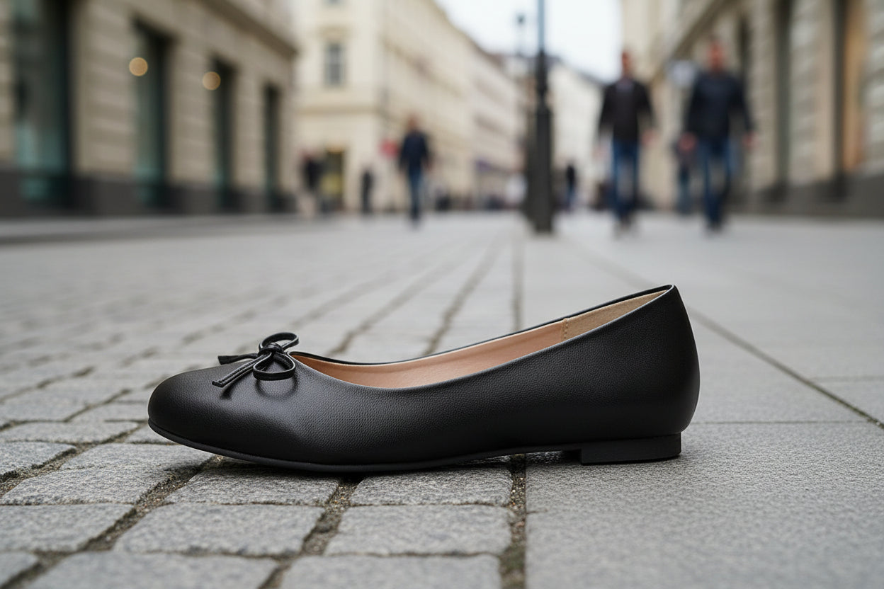 Black ballet flat shoe on a city street with blurred pedestrians in the background