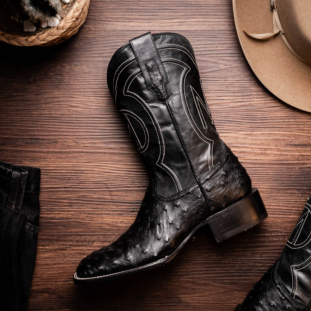 Alabama Black genuine ostrich skin cowboy boot on wooden surface with hat