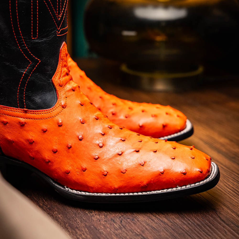 Alabama Orange genuine ostrich skin cowboy boots from Western Collection on wooden surface