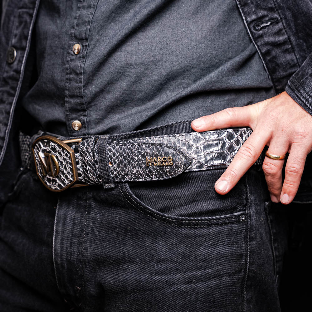Close-up of Arkansas Belt Antique Newspaper with python skin and brass buckle on man wearing black jeans.