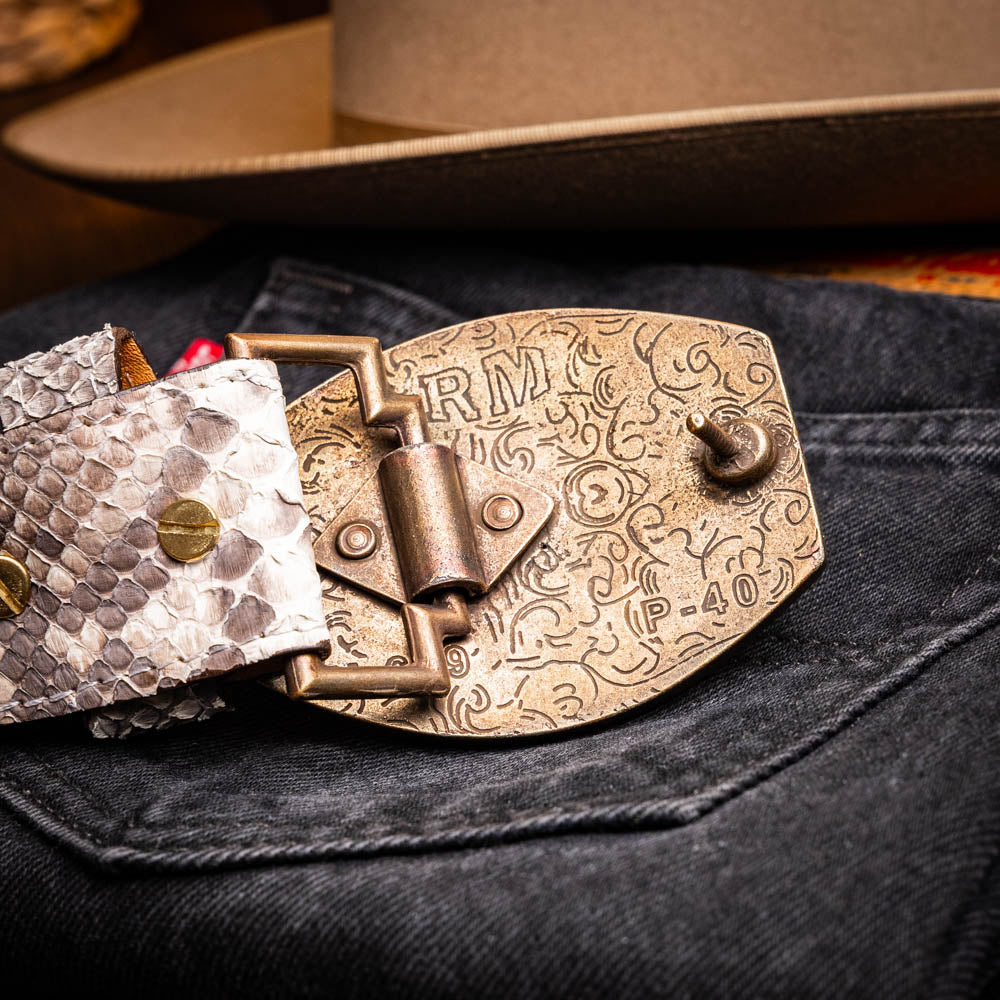 Arkansas Belt Natural with genuine python skin and antique brass buckle displayed on denim fabric.