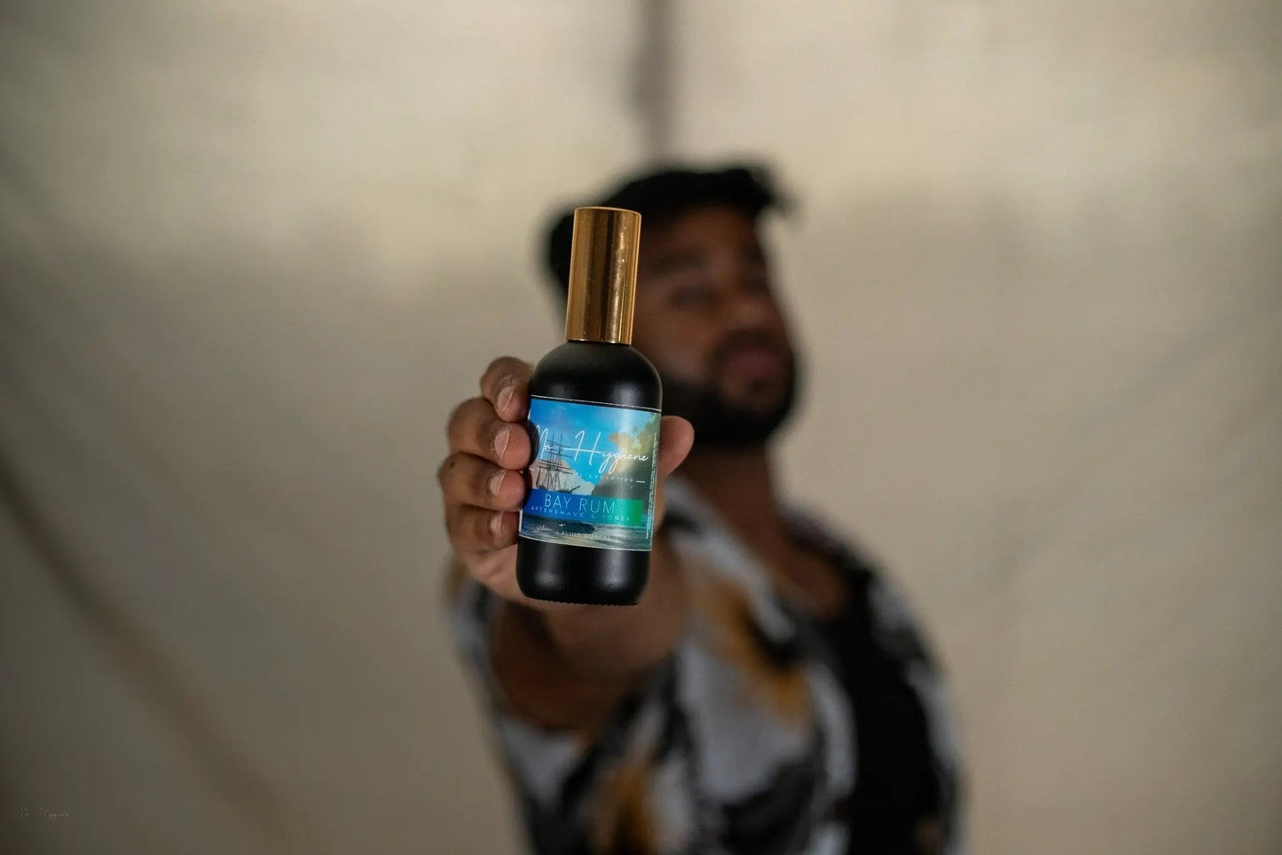 Man holding Bay Rum Aftershave bottle showcasing its invigorating scent and nourishing formula for men's skin care.