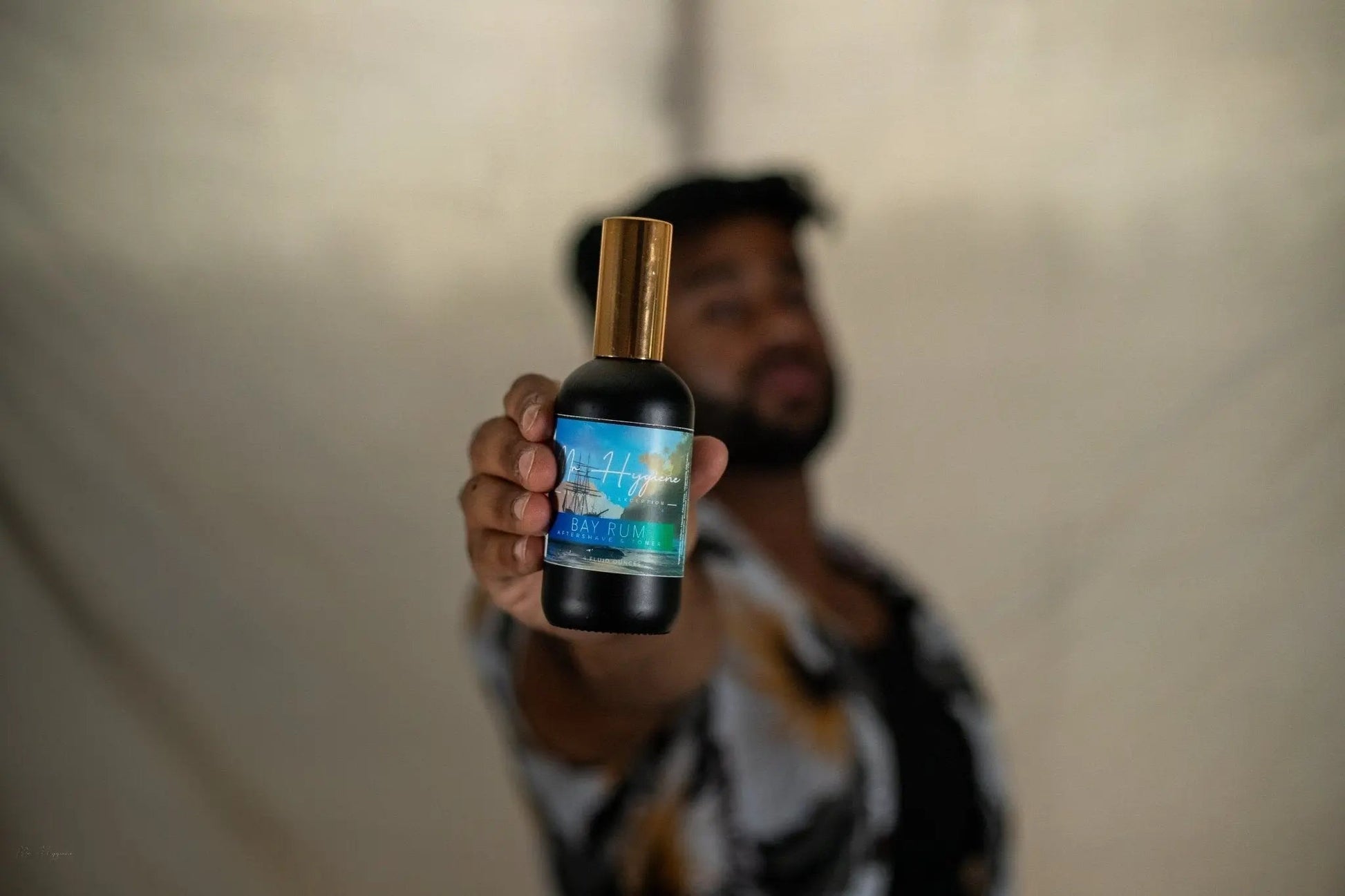 Man holding Bay Rum Aftershave bottle showcasing its invigorating scent and nourishing formula for men's skin care.