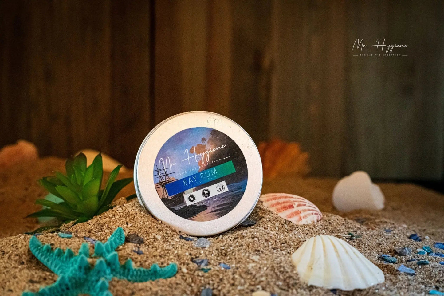 Bay Rum Beard Balm – Bold Scent & Daily Control tin in a beach-themed setting with shells and sand.