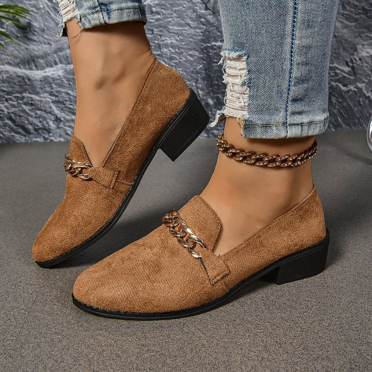 Stylish brown loafers with chain detail, worn with distressed jeans for a relaxed look.