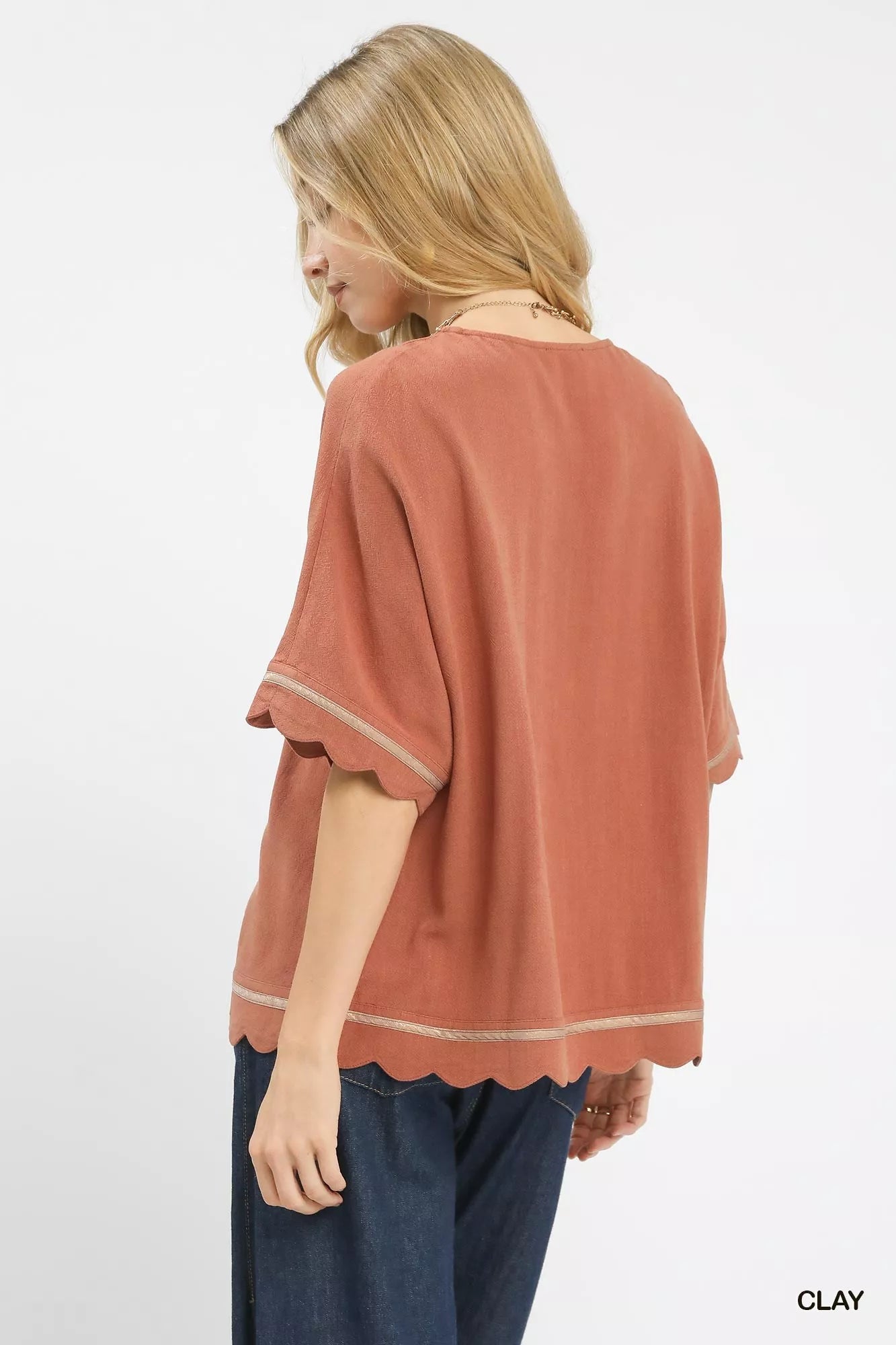 Woman wearing Umgee Linen Blend Scallop Trim Top in clay color, showcasing scalloped edges and relaxed fit from the back view.