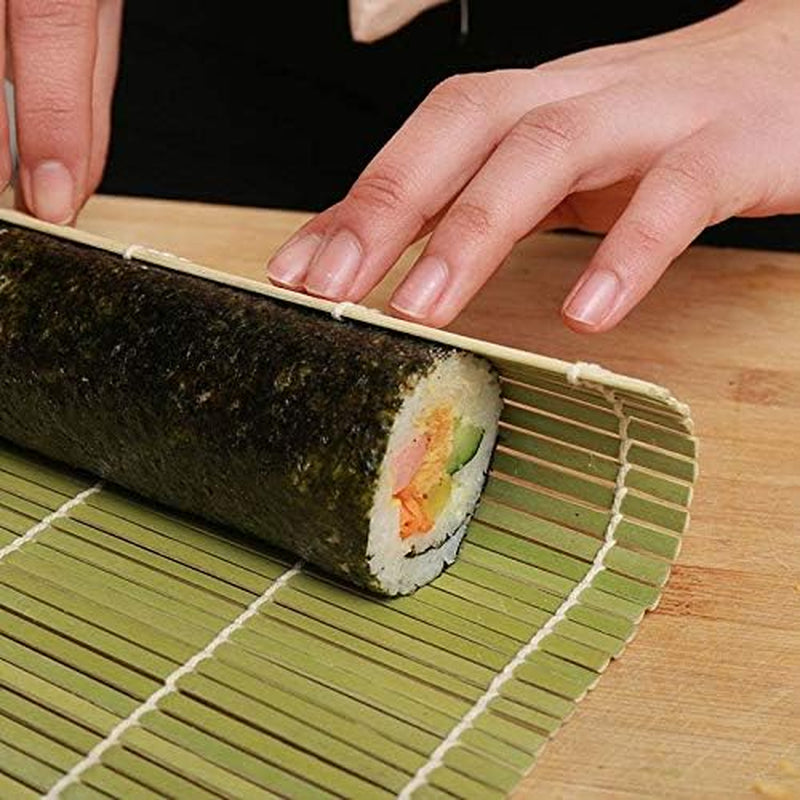 Person rolling sushi with Bamboo Sushi Rolling Mat & Rice Paddle Set (3-Piece) on a wooden board.