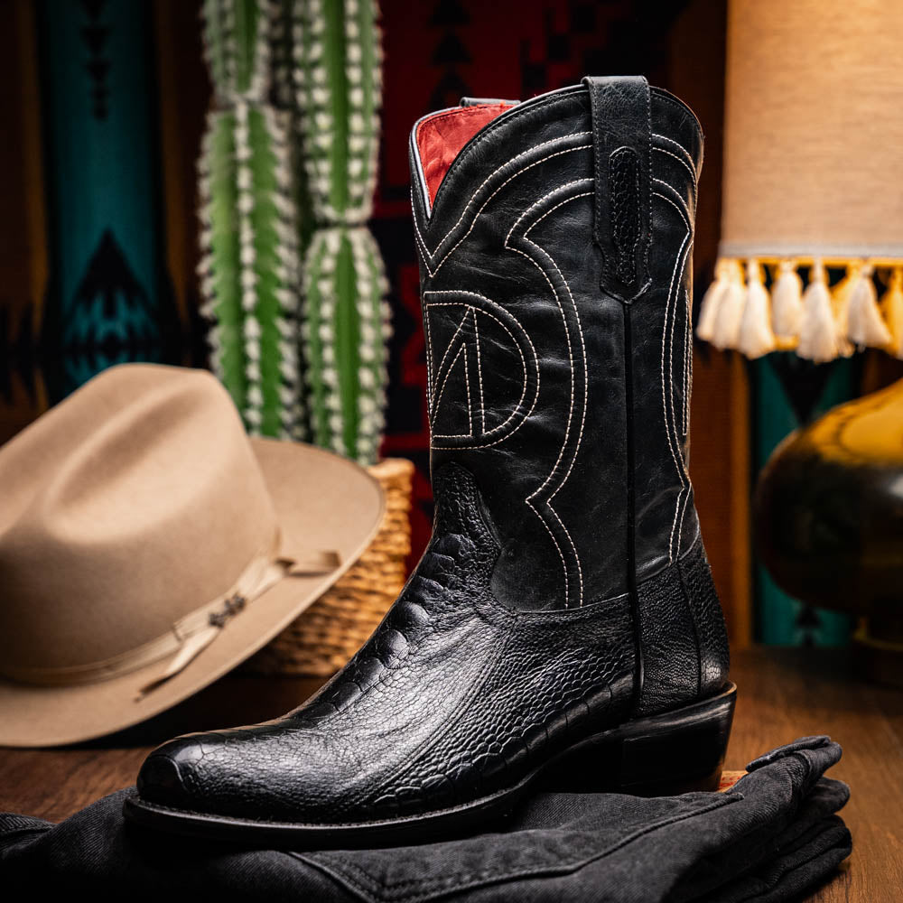 Denver Black Ostrich Leg Skin Cowboy Boot on display with western decor