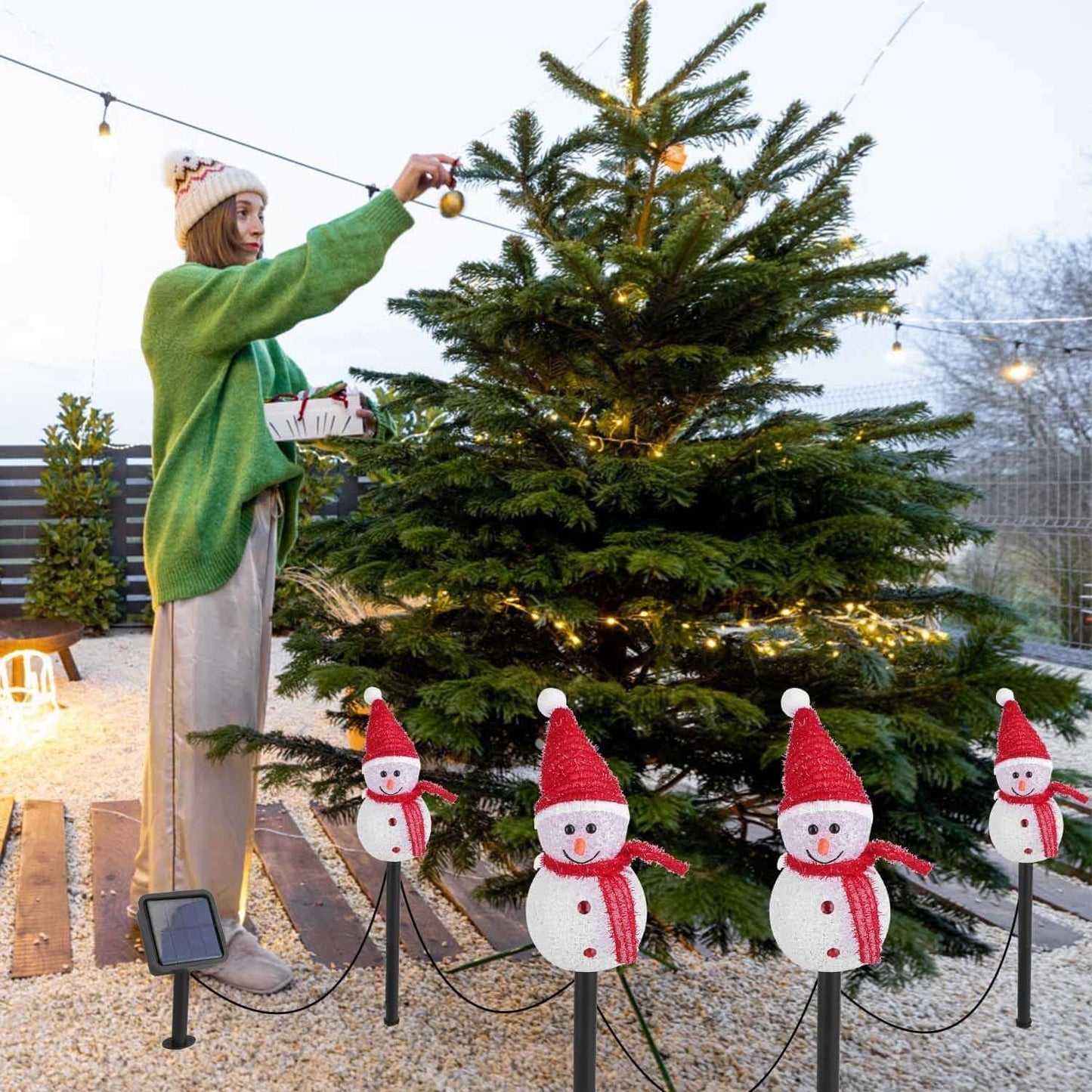 Solar Powered Christmas Lamp with 3 Snowmen Garden Stake lights illuminating a festive outdoor scene with a Christmas tree.