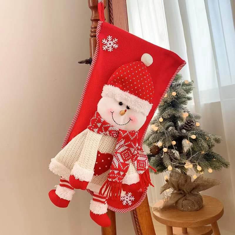 Red Christmas Stocking Decorations with Santa Claus design hanging beside a decorated mini Christmas tree.