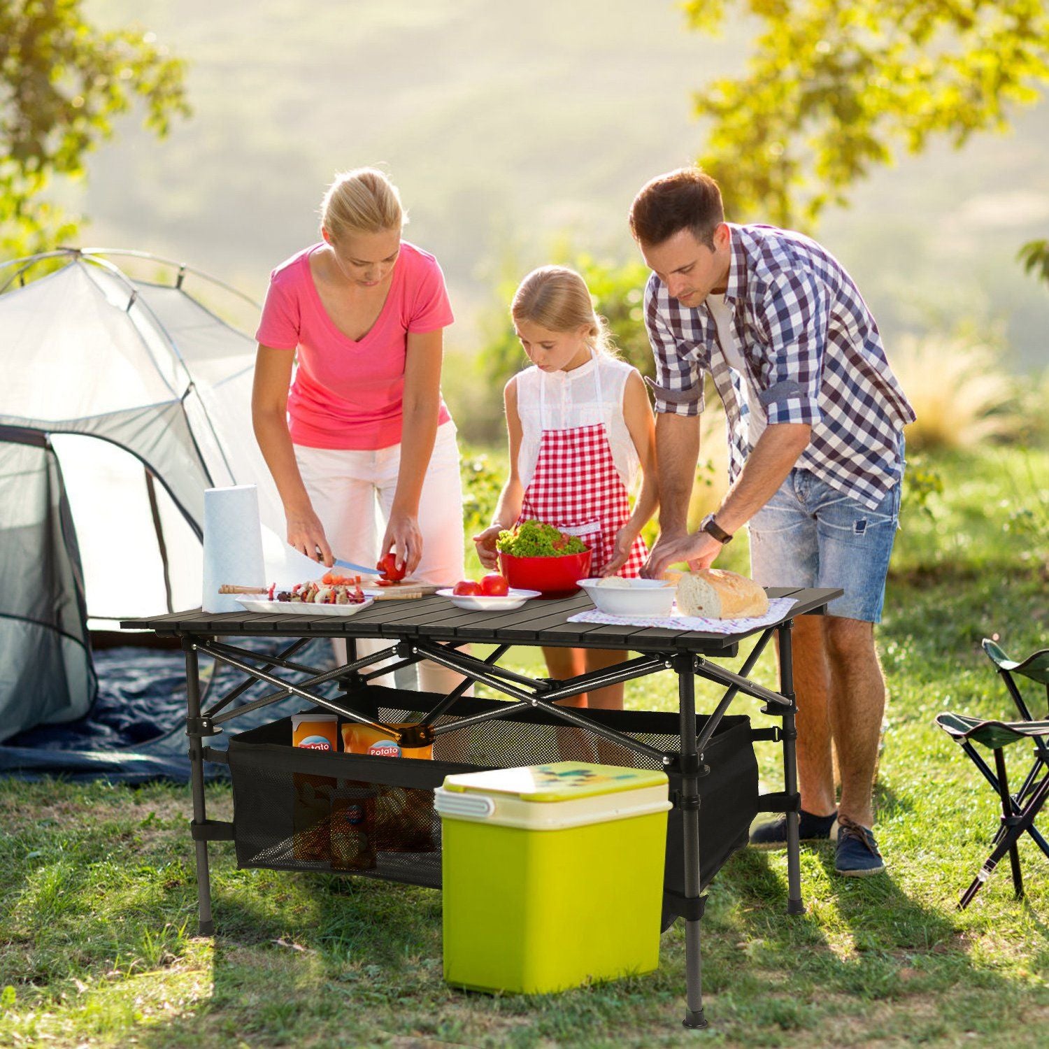 Family enjoying a picnic with folding camping table, portable and lightweight aluminum design, featuring a roll-up top and storage basket.