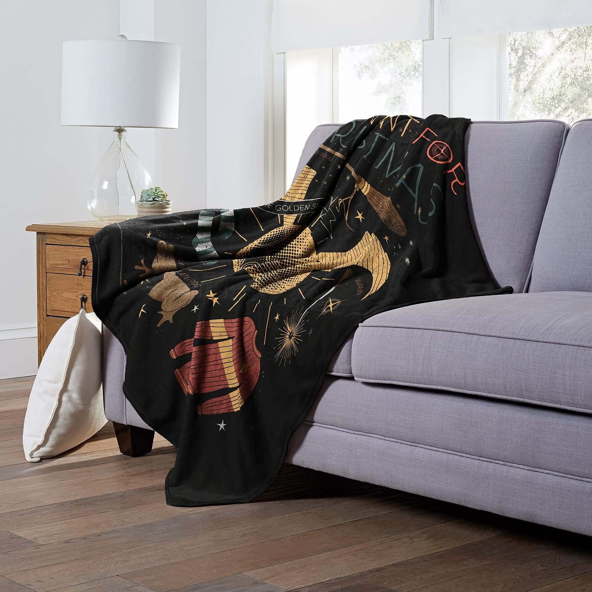 Harry Potter Silk Touch Throw Blanket displayed on sofa, showcasing All I Want For Christmas design, ideal for cozy evenings.