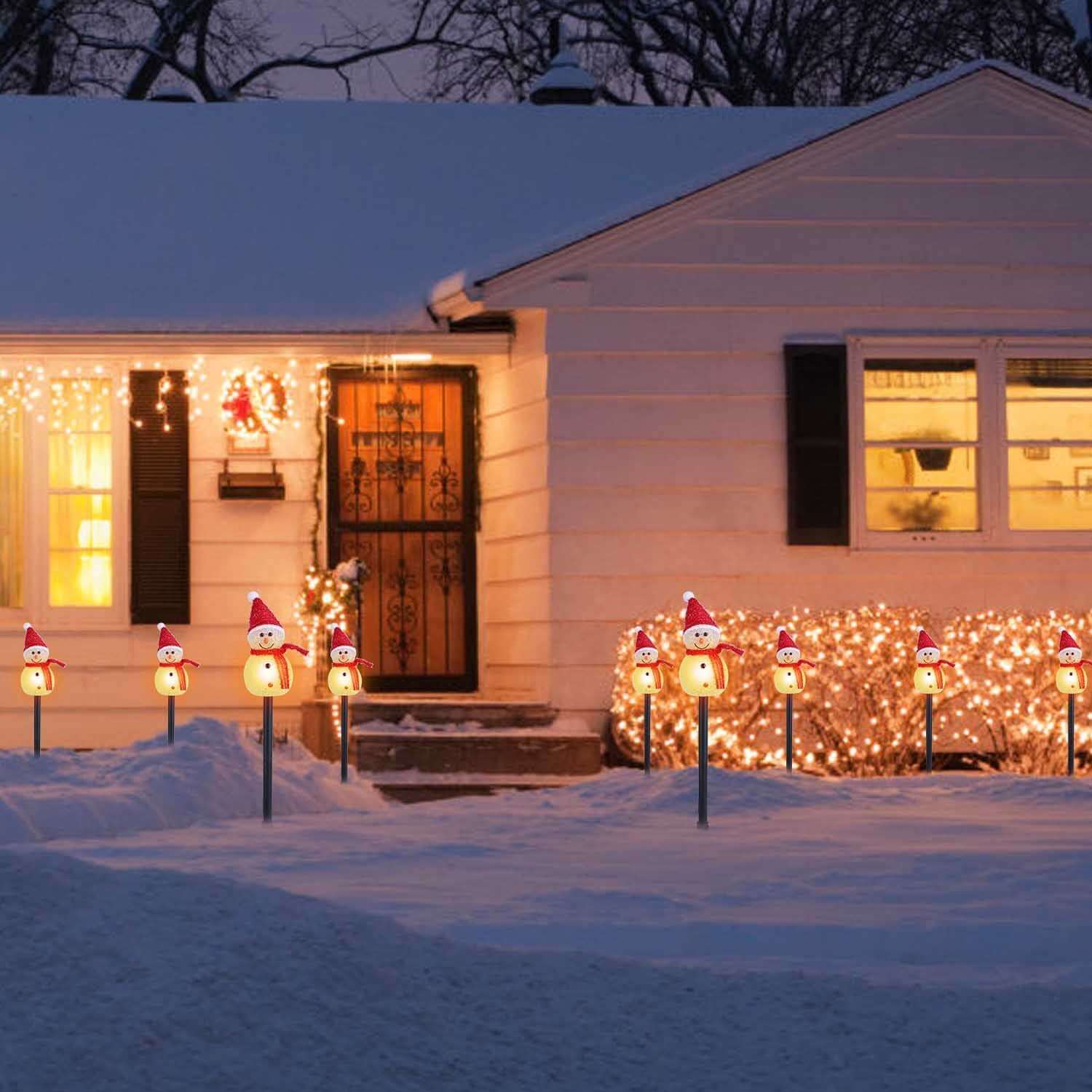 Decorative Solar Powered Christmas Lamp with 3 Snowmen Garden Stakes lighting pathway, IP55 waterproof, at night in snowy yard.