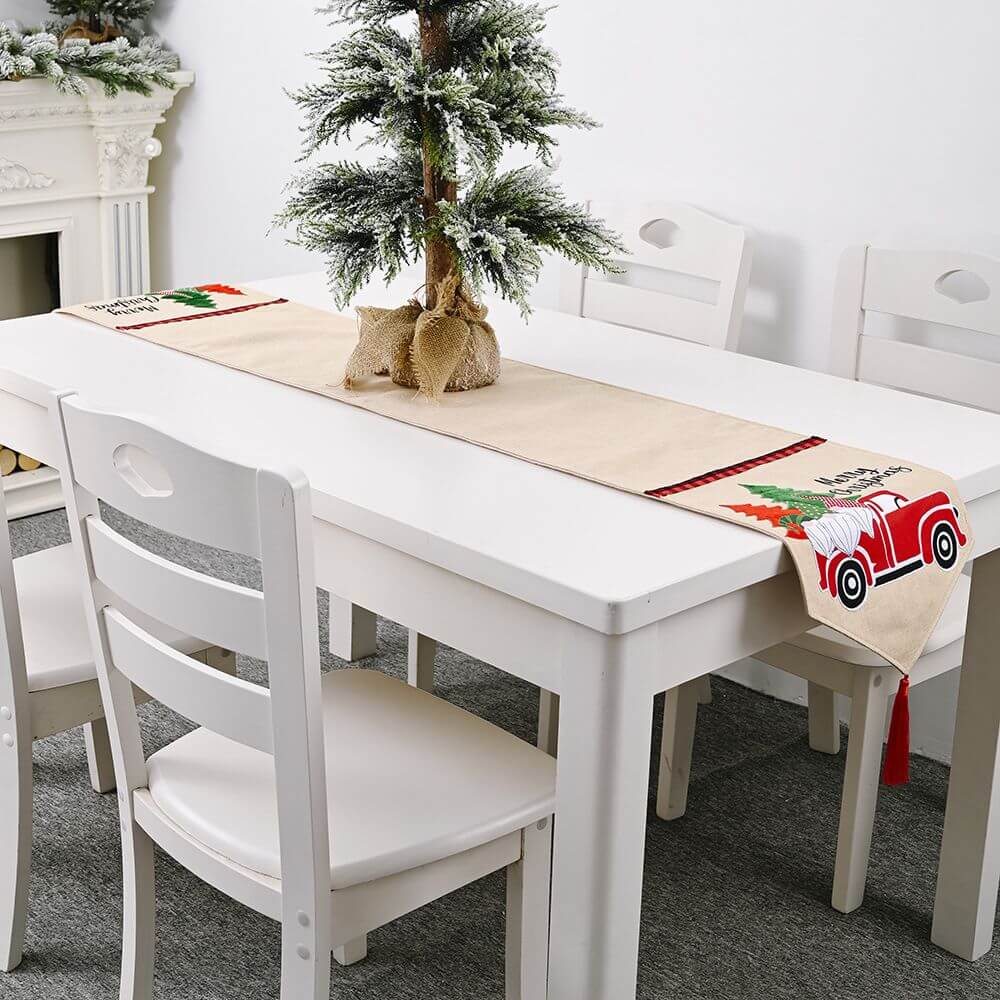 Festive Christmas Santa Claus Car Table Runner on a white dining table with a mini tree centerpiece, perfect for holiday home decor.