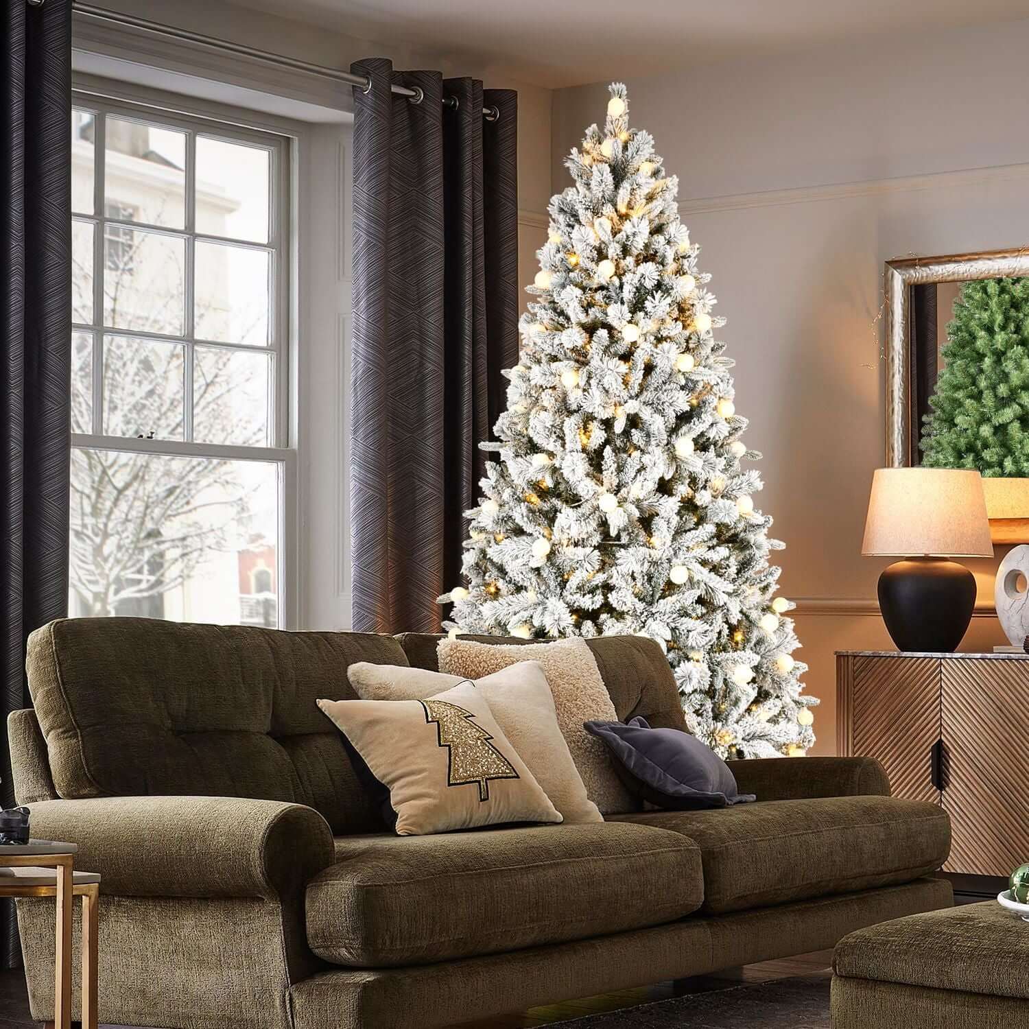 Living room with elegant Flocked Christmas Tree with Colorful Lights, showcasing a snowy appearance and festive charm.