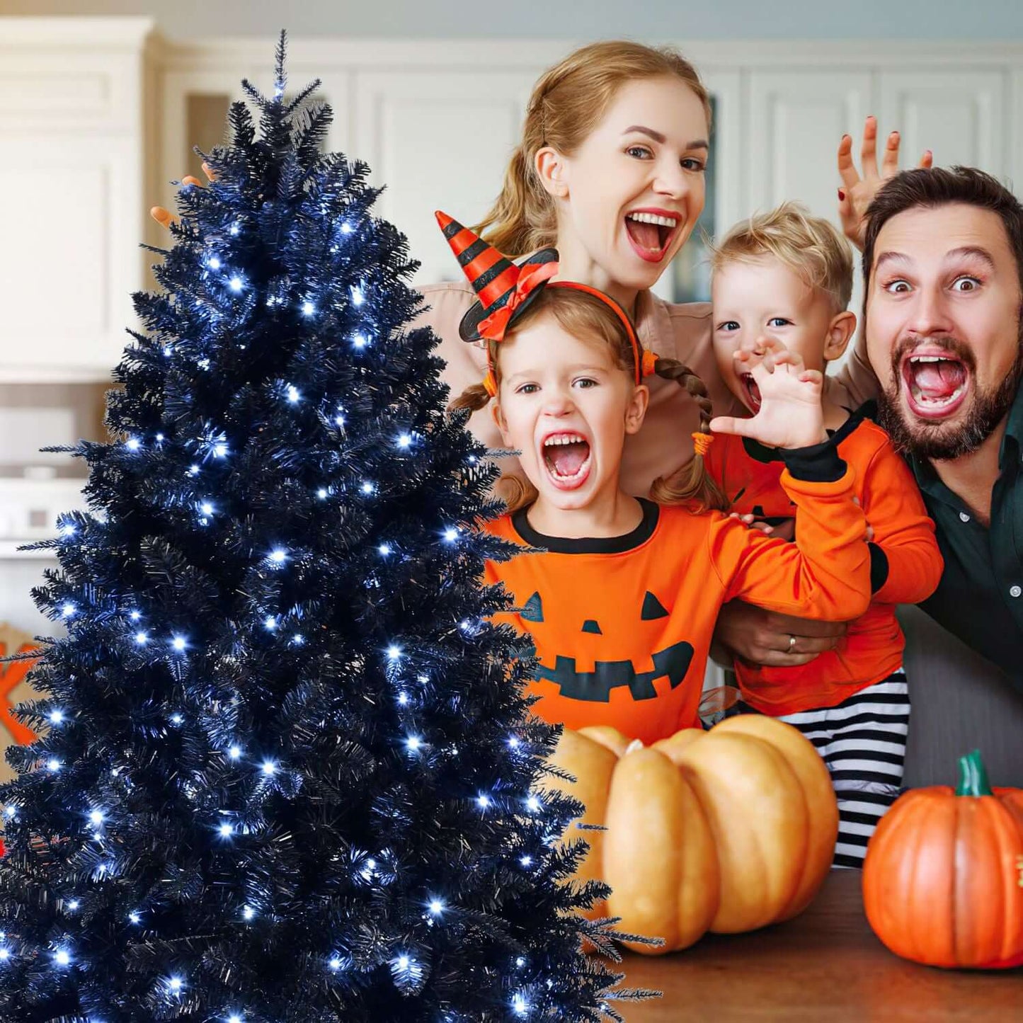Family celebrating with Black Christmas Tree with White LED Lights in a Halloween-themed setting with pumpkins.