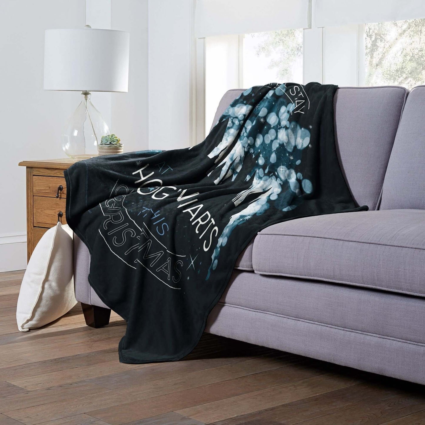 Harry Potter Hogwarts Christmas Throw Blanket draped over a couch, showcasing magical Hogwarts design.