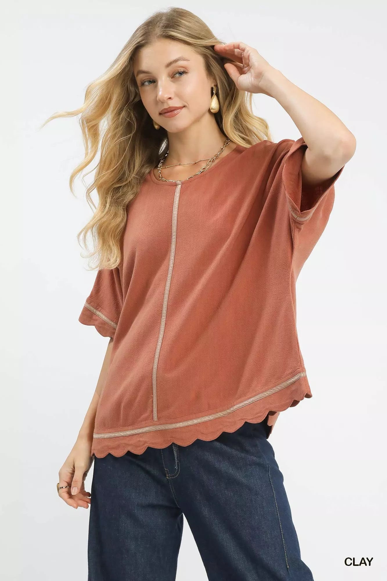 Woman wearing Umgee Linen Blend Scallop Trim Top in clay, showcasing scalloped edges and short dolman sleeves.