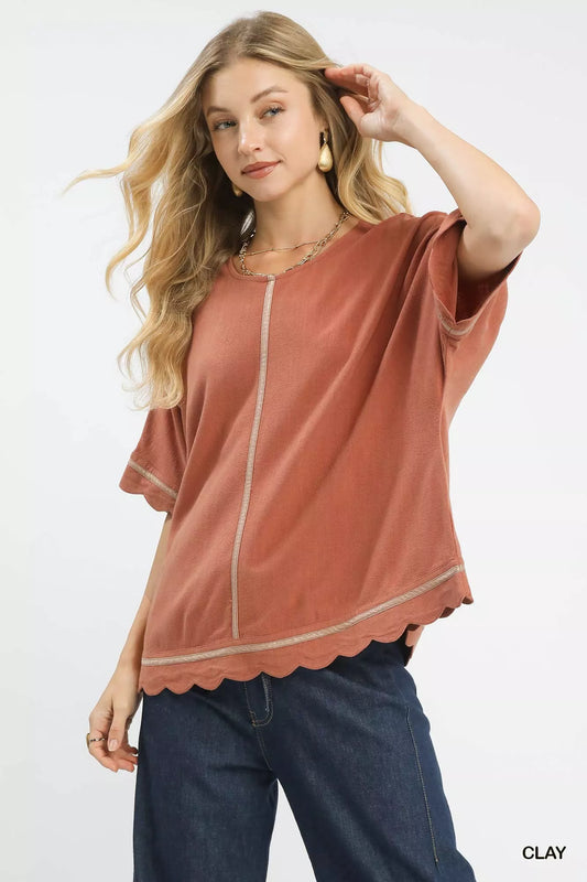Woman wearing Umgee Linen Blend Scallop Trim Top in clay, showcasing scalloped edges and short dolman sleeves.