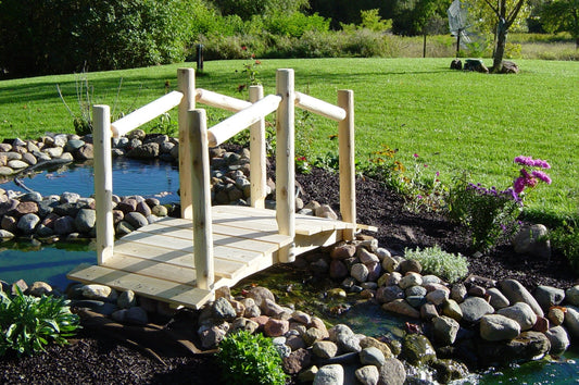 Decorative Garden Bridge made of premium white cedar logs, serving as a focal point in a landscaped outdoor setting.
