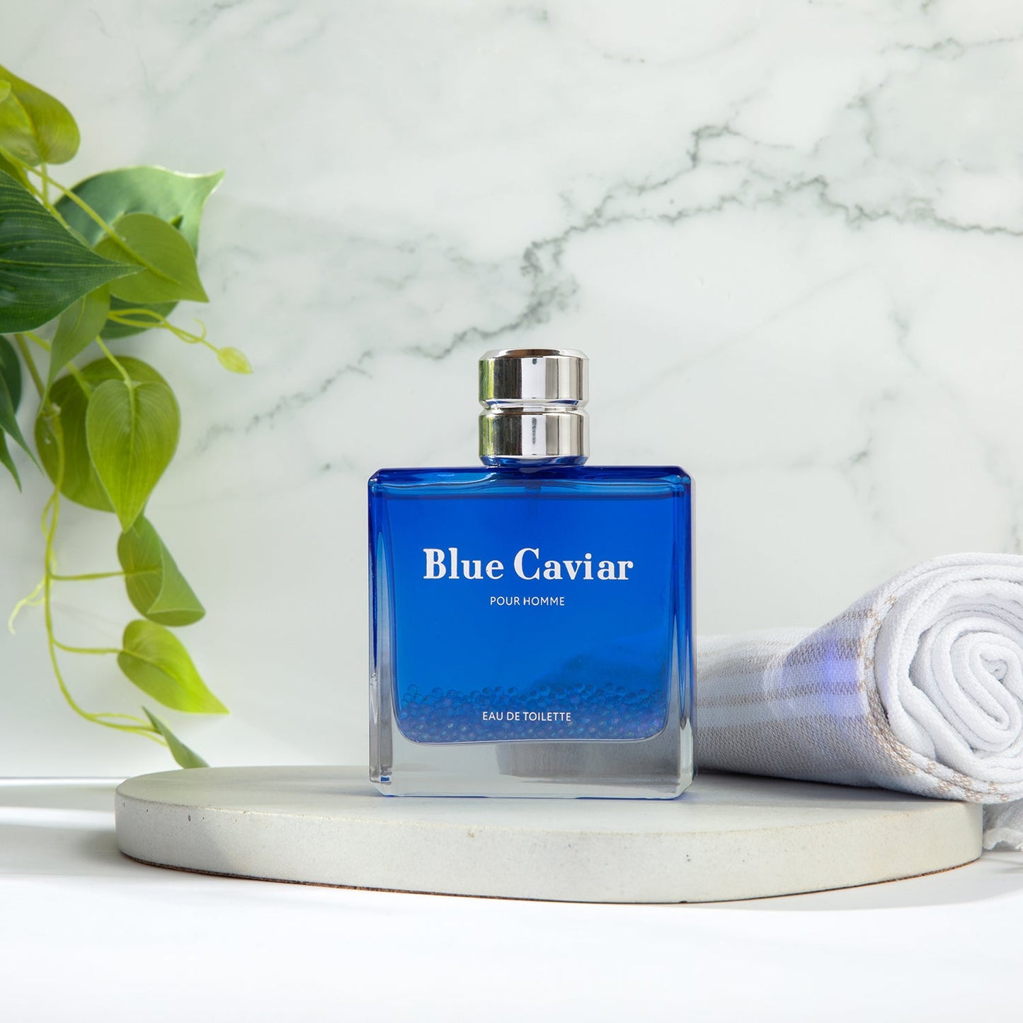 Syren - Blue Caviar fragrance bottle on marble surface with green plant
