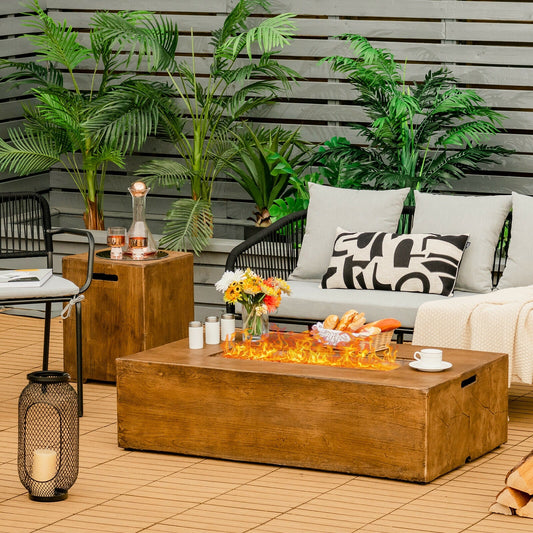 2 Piece Outdoor Propane Fire Pit Table Set with tank holder and lava rocks on a patio with plants and seating
