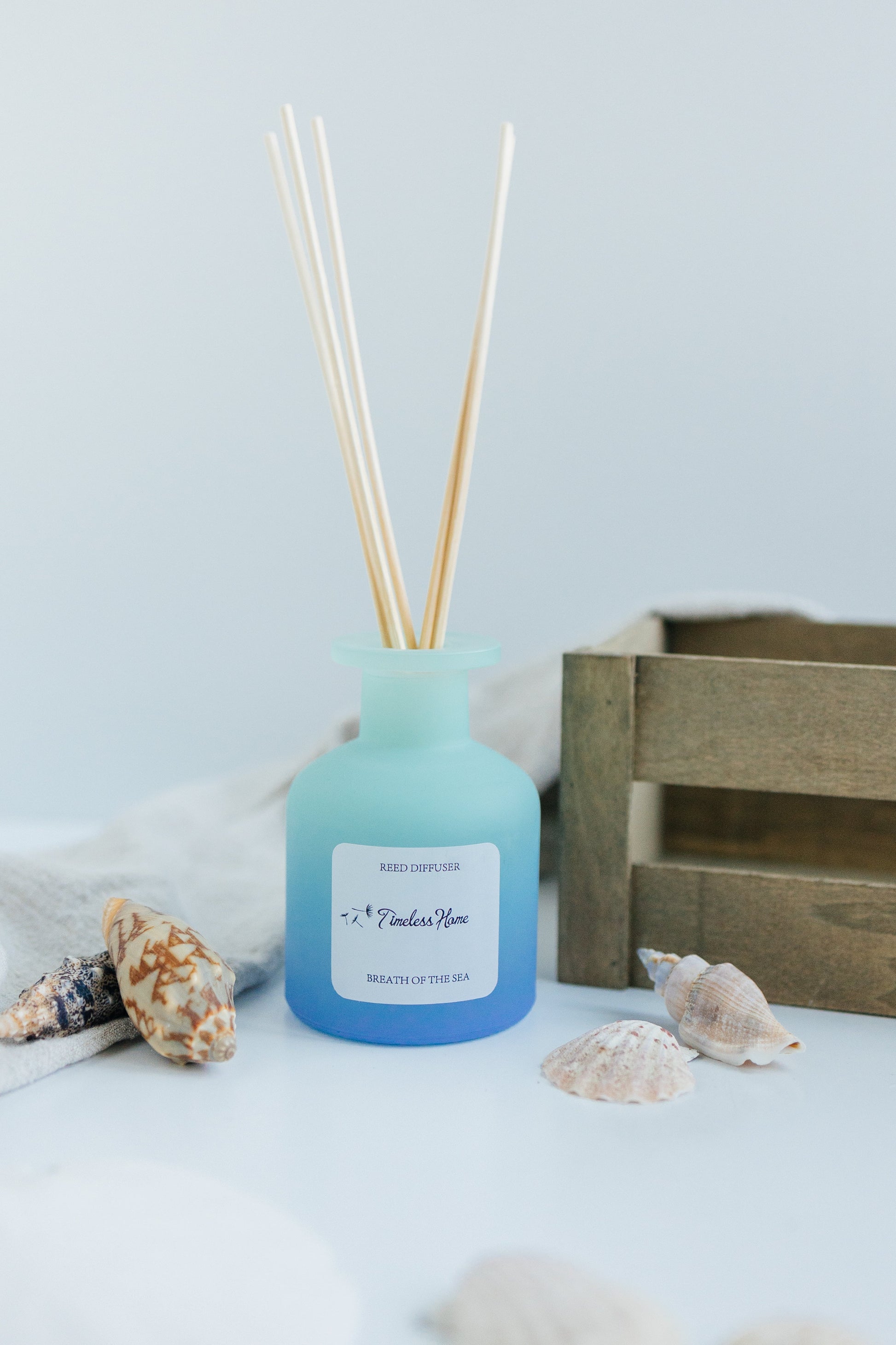 Reed Diffuser - Breathe of The Sea with ocean & lemon scent in custom frosted glass, surrounded by seashells.