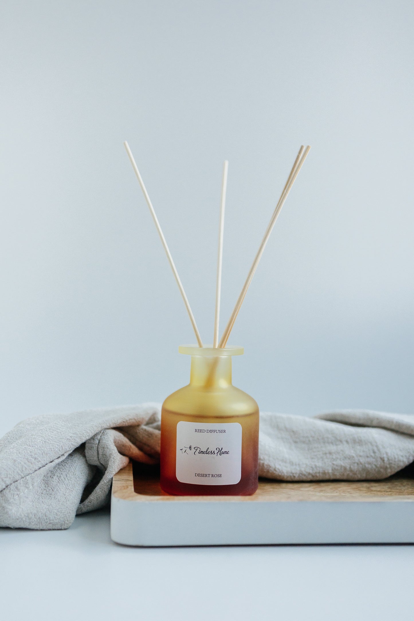Reed Diffuser - Desert Rose in frosted glass with natural reed sticks, luxurious long-lasting fragrance with rose, oak, and patchouli notes.