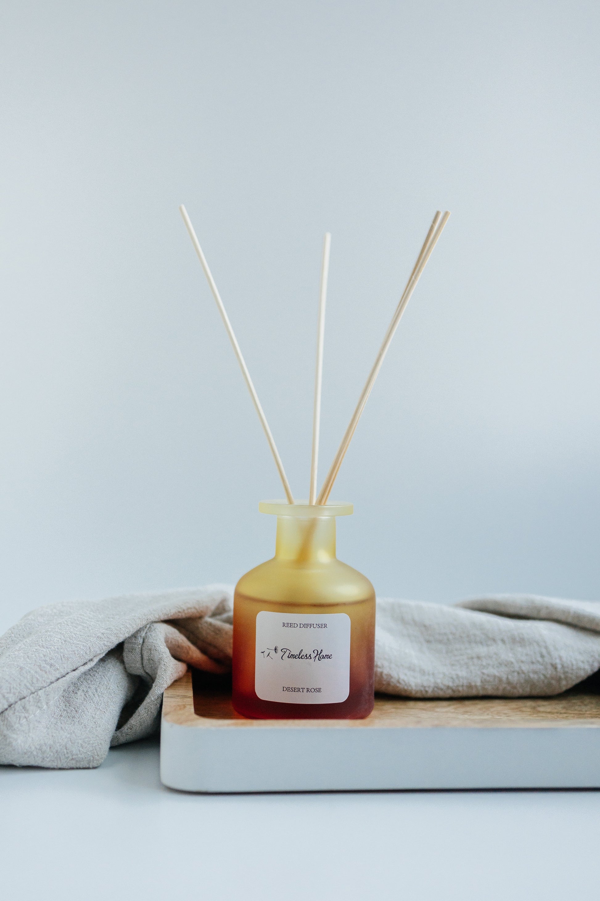 Reed Diffuser - Desert Rose in frosted glass with natural reed sticks, luxurious long-lasting fragrance with rose, oak, and patchouli notes.