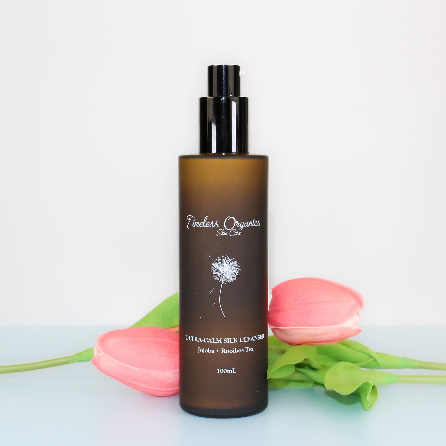 Ultra-Calm Silk Cleanser bottle with floral background, 100ml