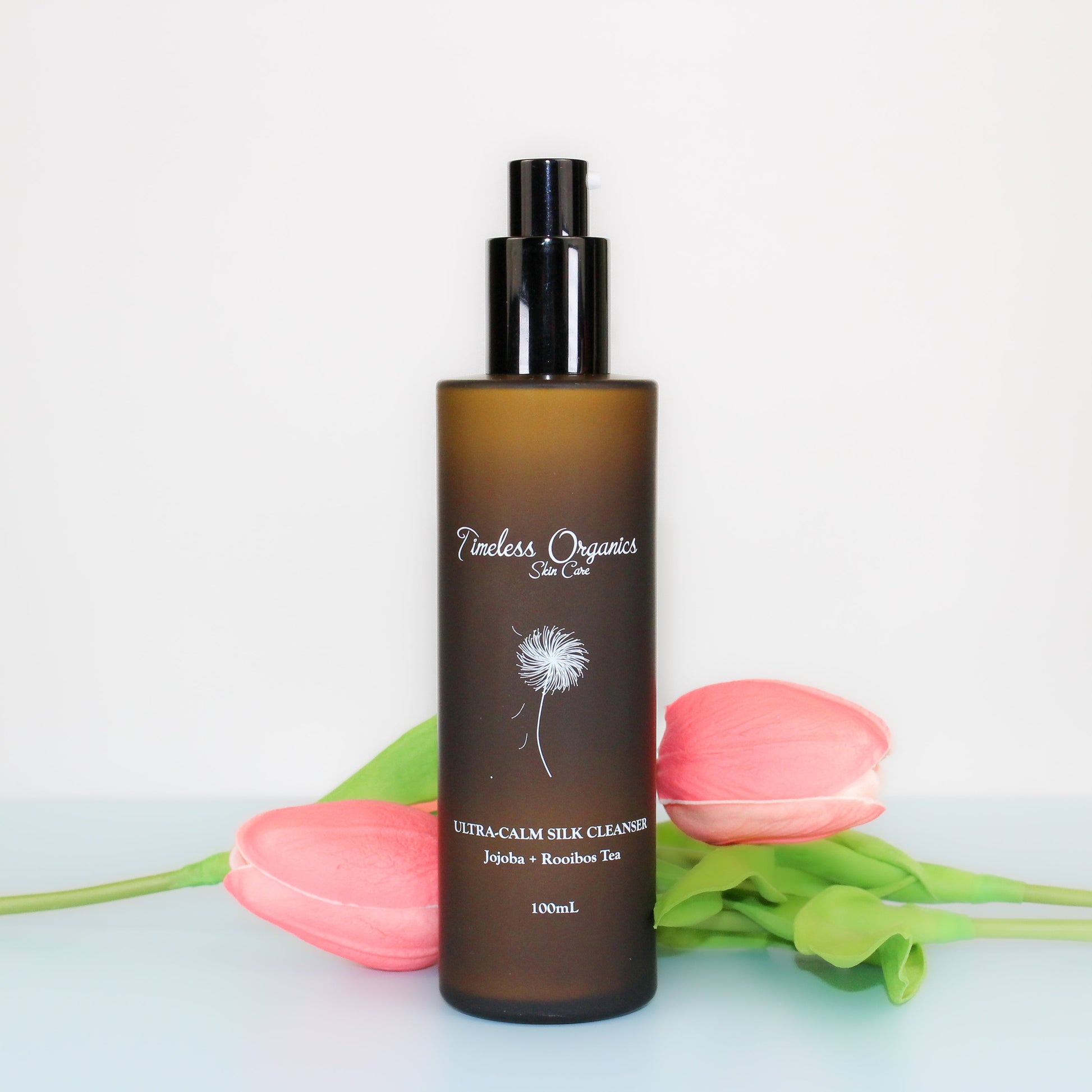 Ultra-Calm Silk Cleanser bottle with floral background, 100ml