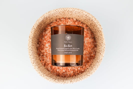 Limited Edition - Sea Salt candle in amber glass, hand-poured organic soy wax with natural essential oils, on pink sea salt bed.