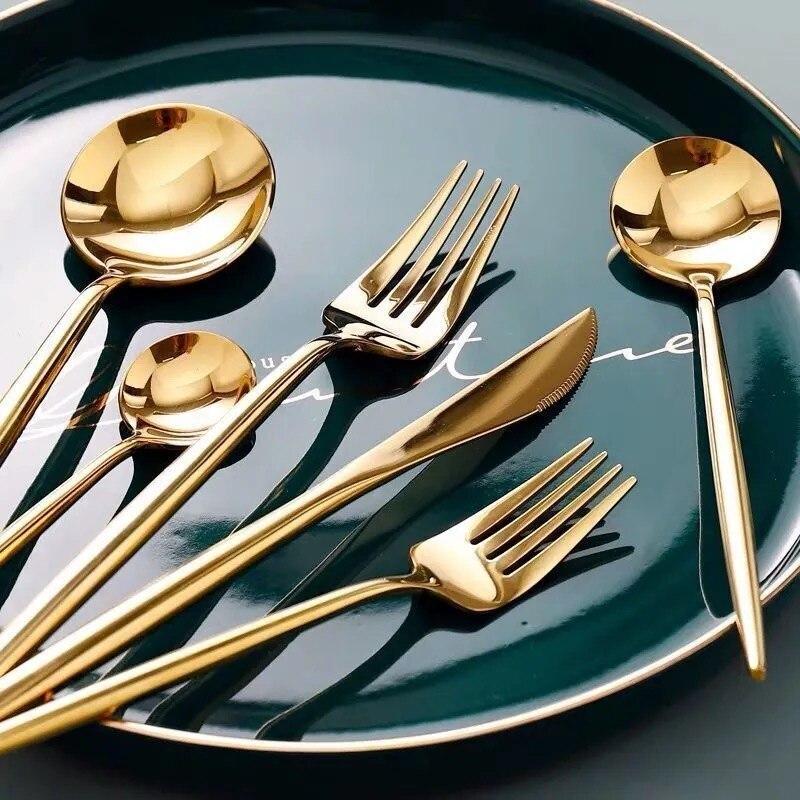 Elegant gold flatware set arranged on a green plate featuring the Stella 30-Piece Flatware Set in mirror-polished stainless steel.