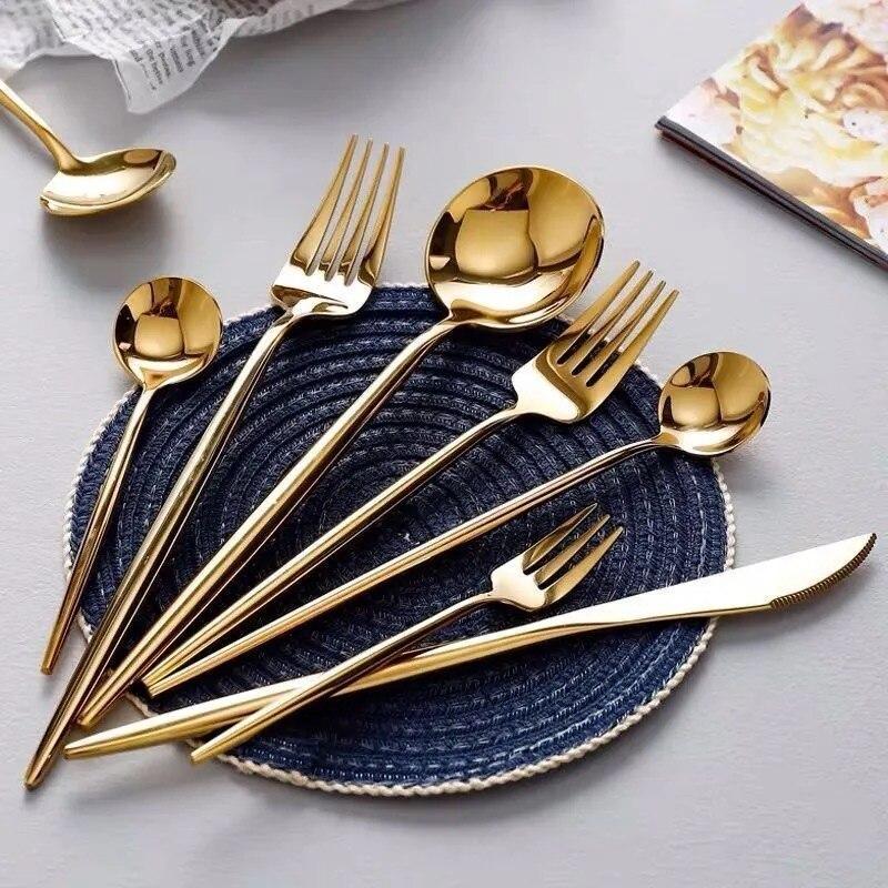 Gold flatware set on a table, featuring spoons, forks, and knives with elegant design similar to Stella 30-Piece Flatware Set.