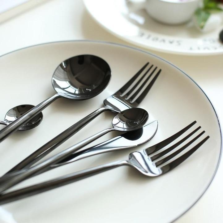 Stella 30-Piece Flatware Set on a dining table with mirror-polished stainless steel finish and delicate oval handles.