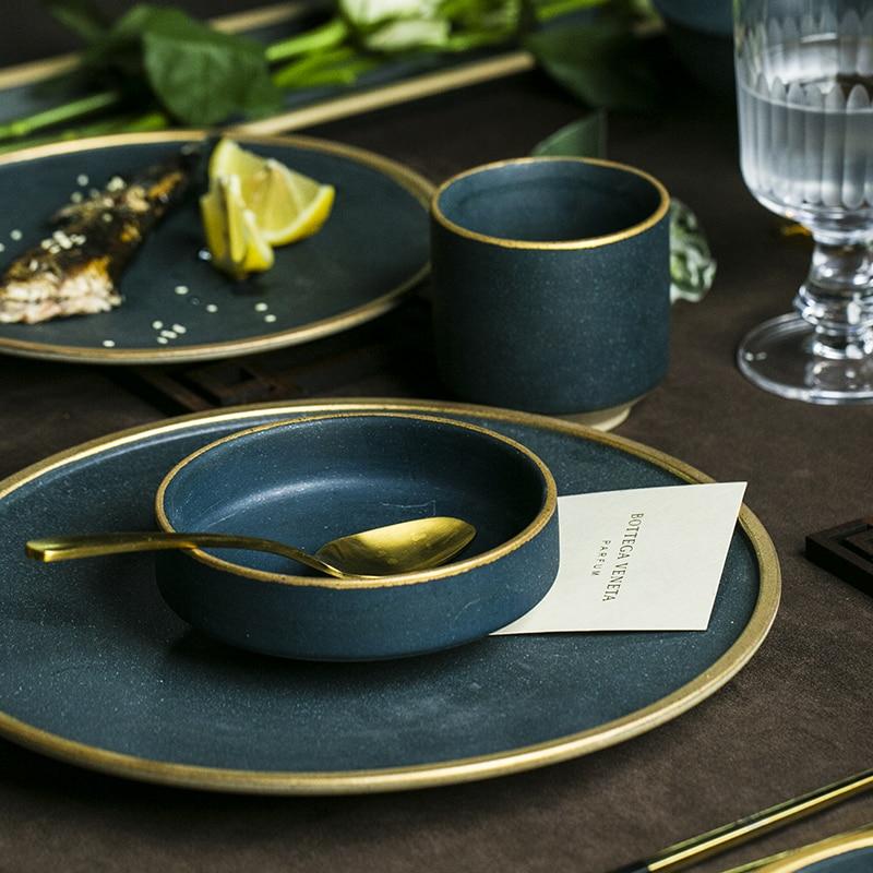 Galileo Tableware set featuring handcrafted porcelain plates and bowls with matte green glaze and golden rings on a dining table.