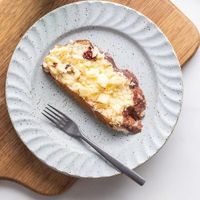 Ceto Nordic Plates with a piece of toast and a fork on a wooden board, showcasing unique ceramic design and Nordic inspiration.