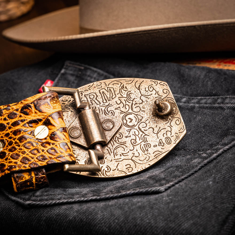 Iowa Belt Mustard Brown with antique brass buckle on denim, showcasing caiman skin and Western design.
